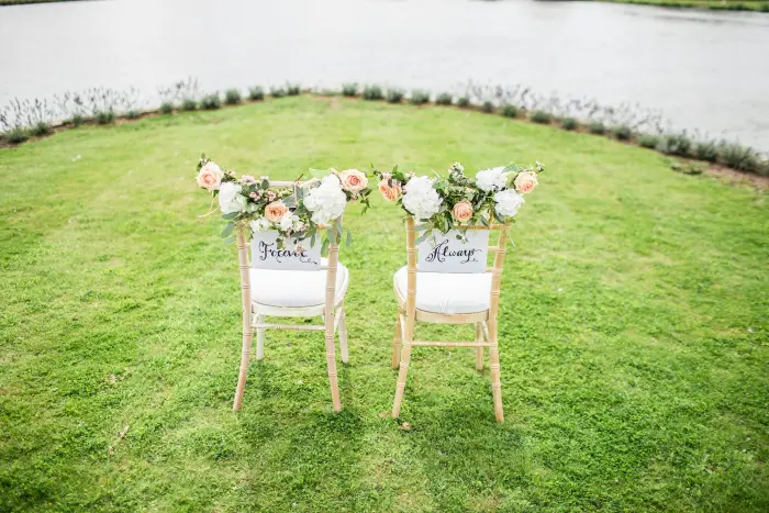 Two wooden chairs decorated with flowers on a green lawn.