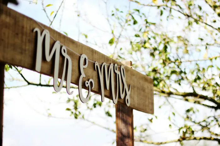 A wooden Mr and Mrs sign hanging from a tree branch.
