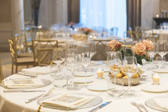 A reception table set with fine china, glassware and peach roses.