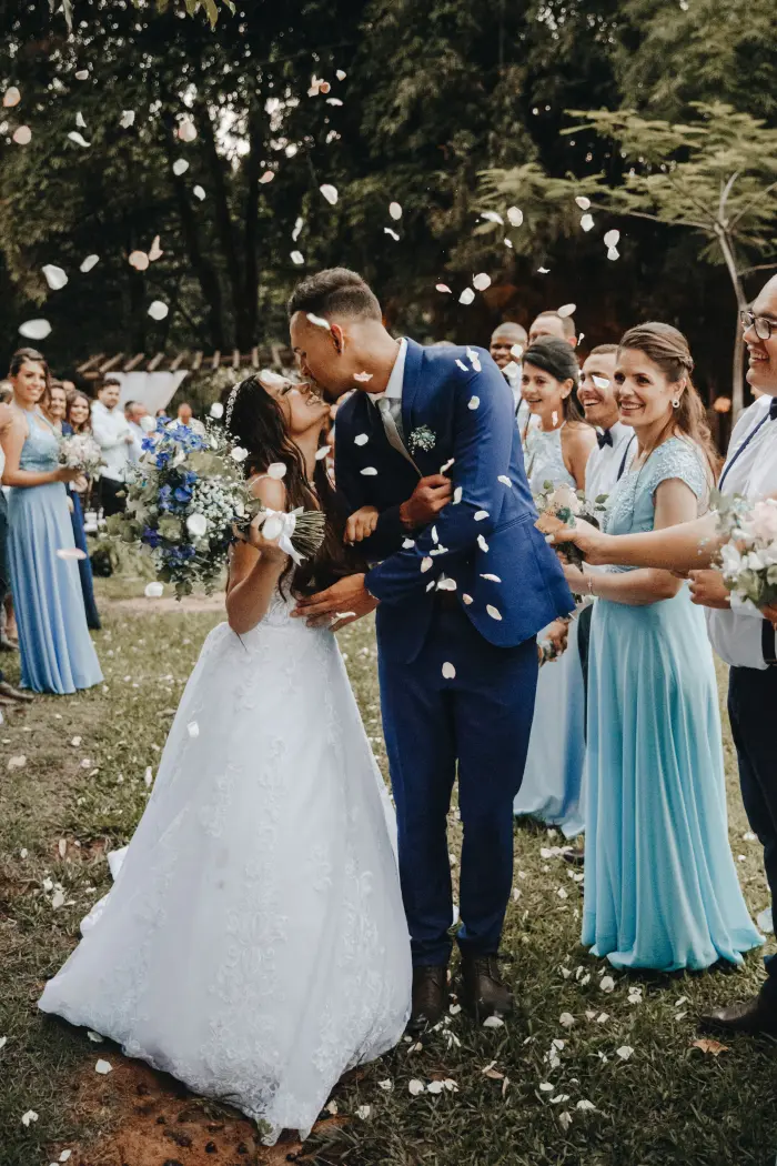 A couple kissing as guests throw confetti.