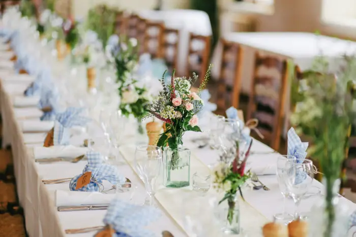 A long reception table set with white and blue linens, flowers and glassware.